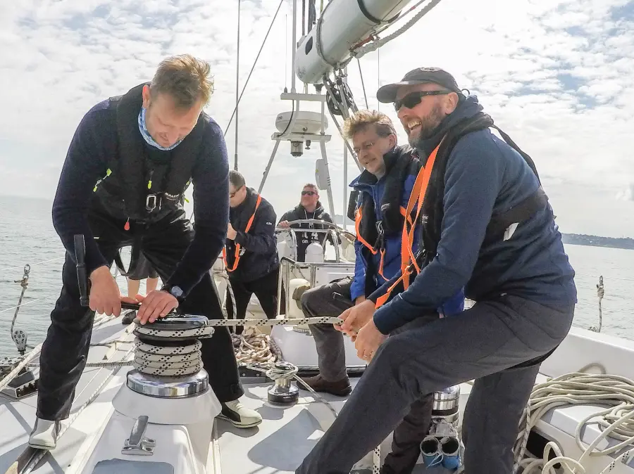 Sailors adjusting genoa trim on offshore passage