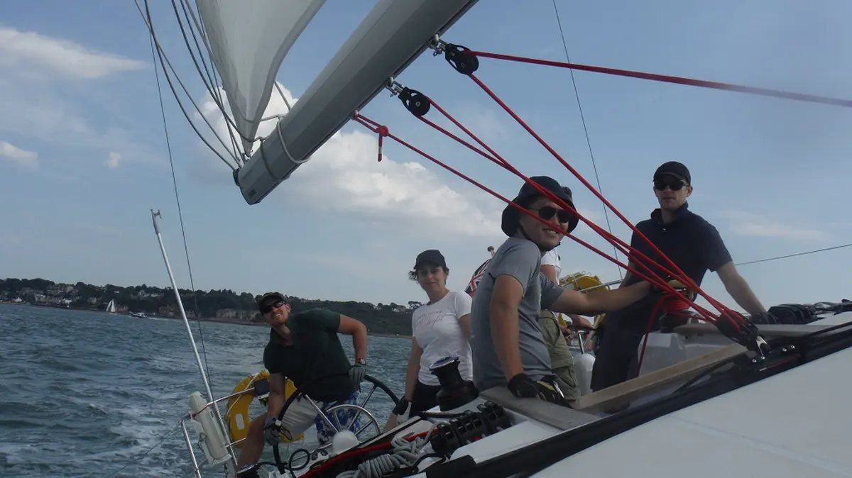 Group of new sailors practising sail hoisting on deck.