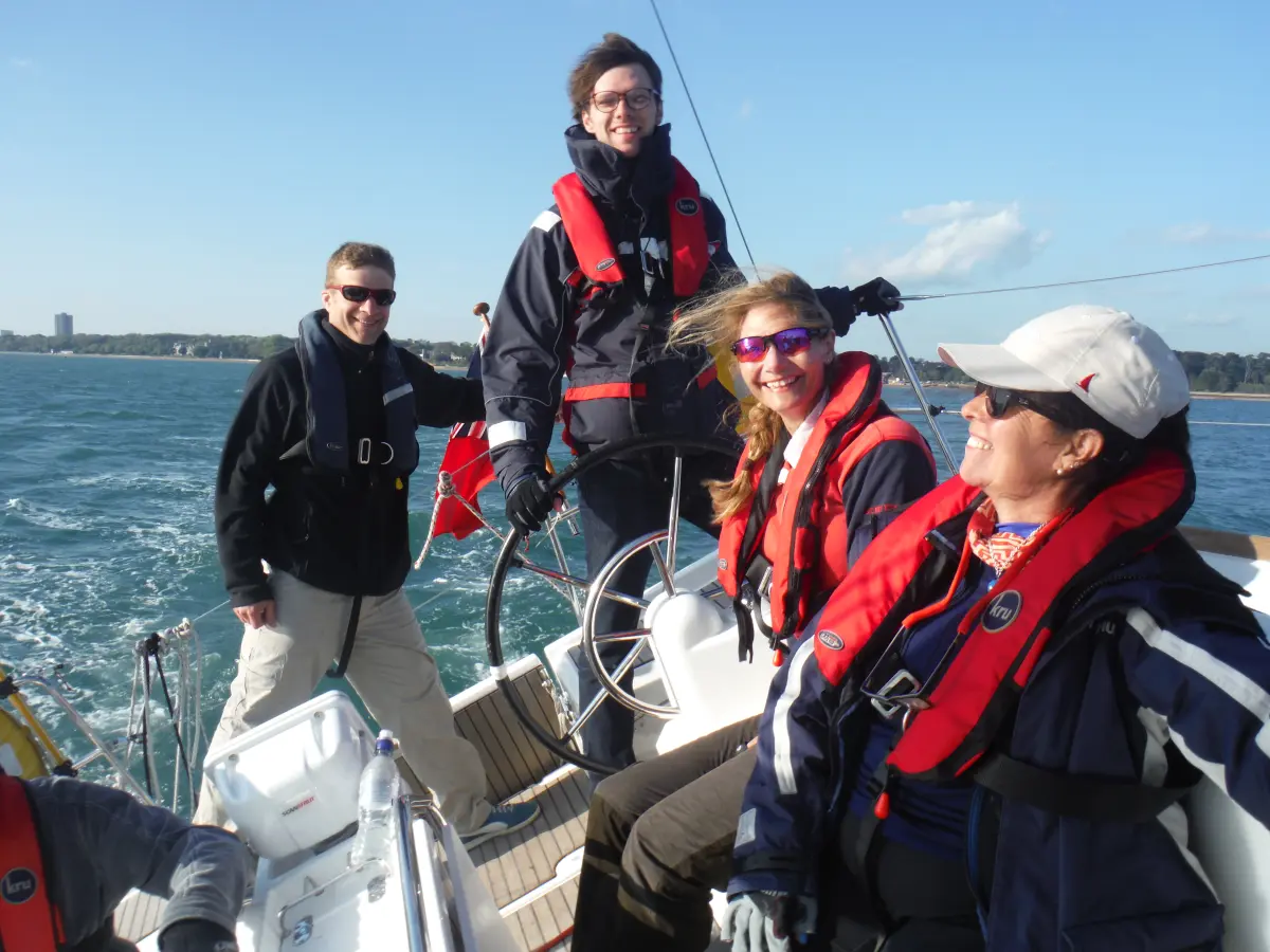 Beginner sailor steering a training yacht during an RYA session.