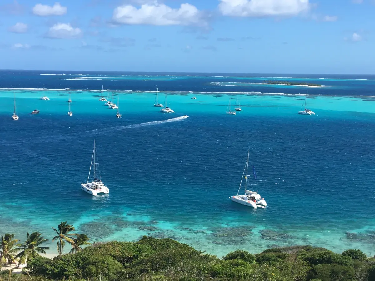 Yachts at anchor off a Caribbean Island behind a sheltering reef