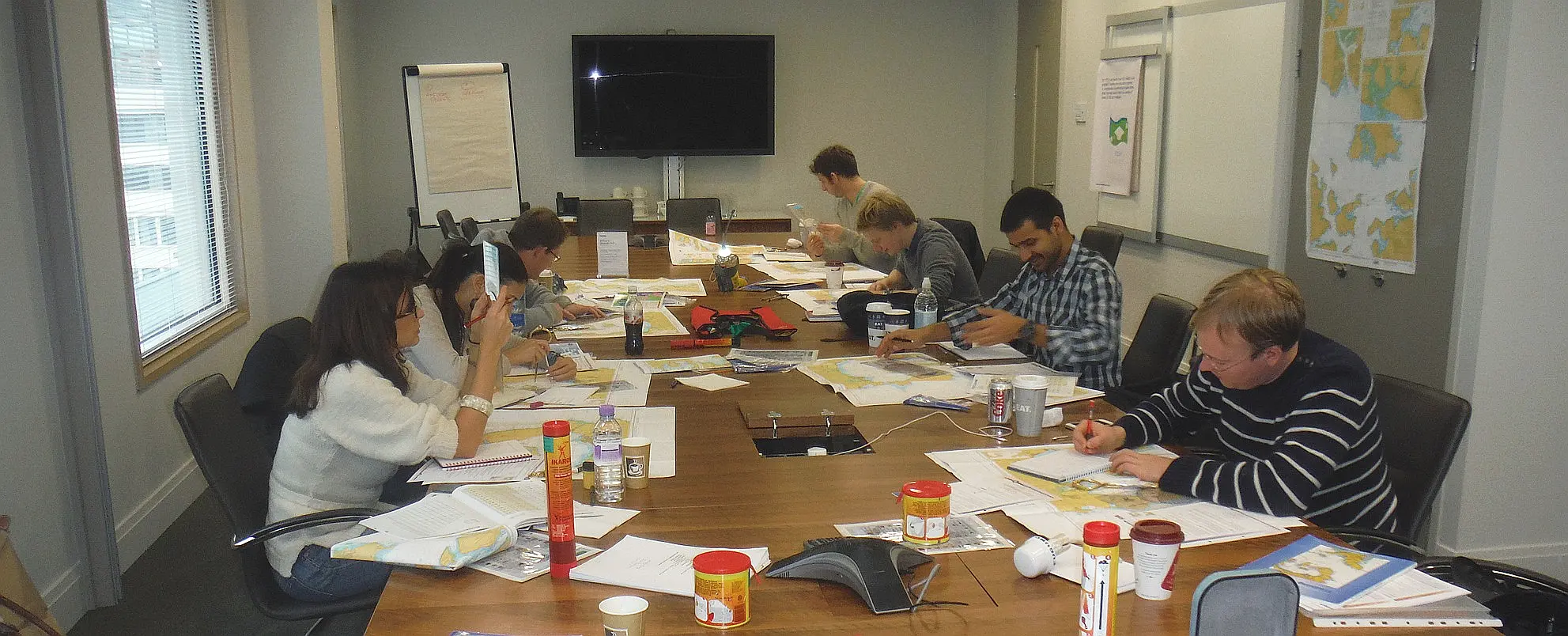 Colleagues learning chartwork and navigation skills together after work